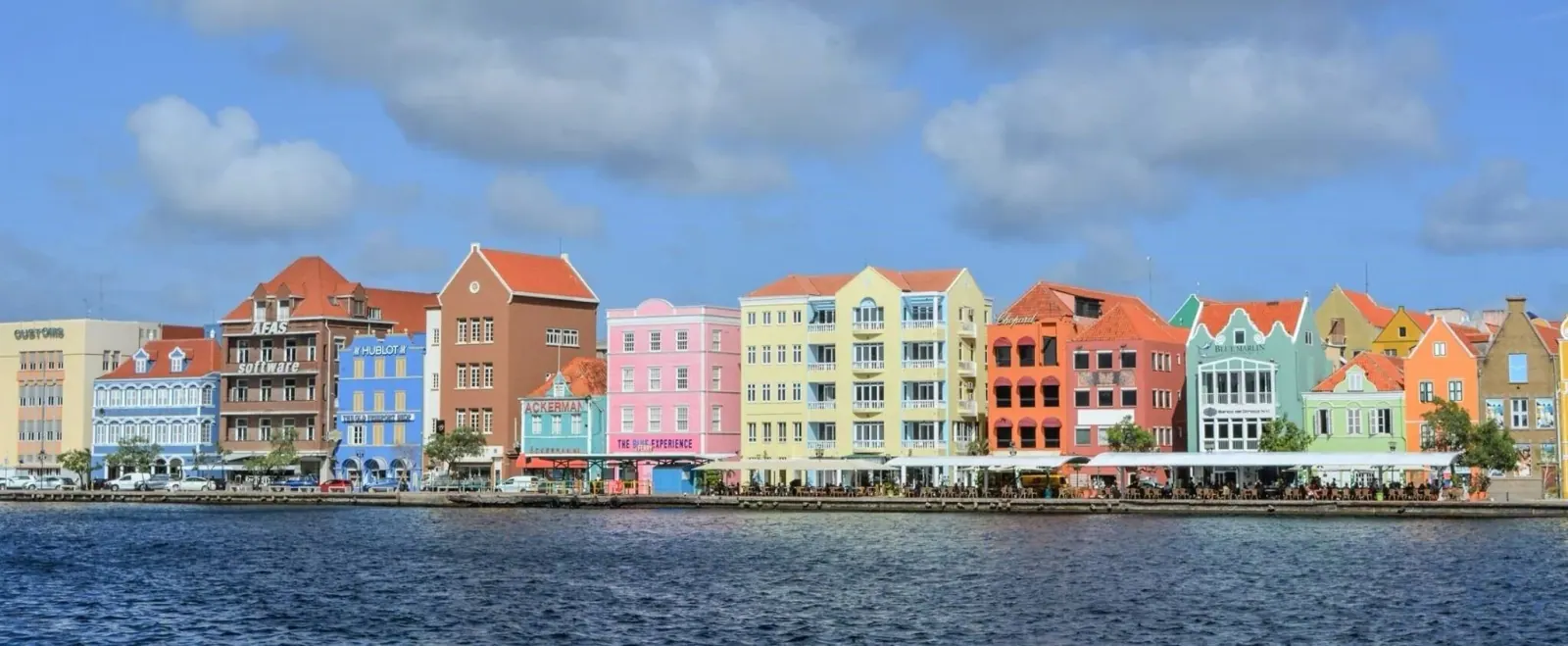 The row of pastel-coloured merchant houses along the Handelskade waterfront in Punda, Willemstad, seen from across the water
